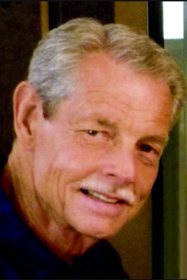 John Barmier, Assistant Department Chair A photo of an older man, John Barnier, with grey, parted hair and a white pencil mustache, wearing a dark blue polo shirt.