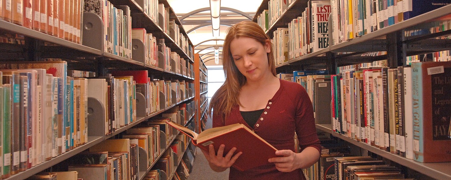 girl reading in library stacks